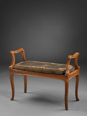  Elegant classical wooden bench with curved armrests and a cushioned seat, featuring a warm honey-brown finish and set against a dark grey background.