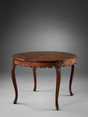  An antique round wooden table with scalloped edges and elegant curved legs, set against a soft gradient gray background.