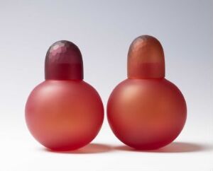  Two rounded glass objects by Trine Drivsholm titled "Red boxes," with a matte finish, showing a transition from deep red at the base to a darker shade at the top, one with a subtle texture on the darker area.