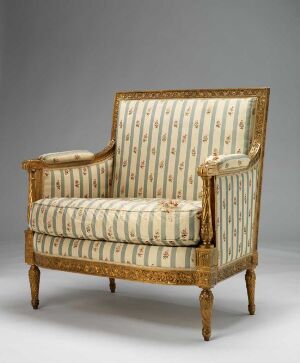  An exquisite gilded beech wood armchair, titled "Fauteuil Causeuse" by an unknown artist, with carved decorations and creamy damask fabric upholstery, featuring vertical stripes and delicate patterns.