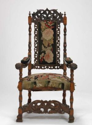  An antique wooden chair with elaborate carvings and a floral tapestry fabric on the seat and backrest, featuring a dark wood finish, intricate details, and a sophisticated, historic design.