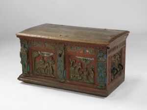  An antique wooden chest with flat top and colorful carved figures in green, red, and teal on the front and sides, featuring animal and foliage-like designs, displayed against a light background. Artistname and title are unknown.