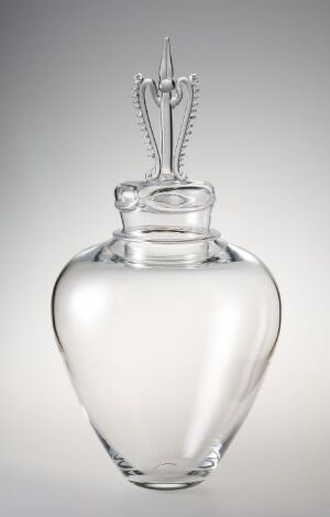 A transparent glass perfume bottle with a curvy base and decorative stopper against a gray gradient background.
