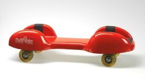  A red children's ride-on toy "Multiroller," designed by Labyrinth Development, featuring a sleek elongated platform with dome-shaped wheel housings on each side, accentuated with black grip pads and yellow-golden wheels.