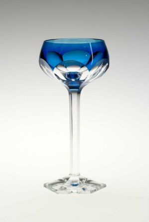   An artistic glass goblet with a wide, shallow bowl and a slender clear stem, featuring a rich blue interior lining against a light grey background.