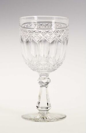  A clear cut-glass goblet with intricate patterns on the bowl and decorative details on the stem and foot, set against a light grey background.