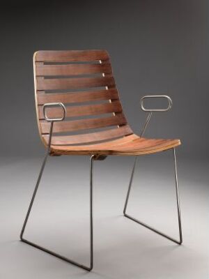  A "Dock High (prototype)" chair designed by Norway Says, featuring form-bent, varnished teak slats on the seat and backrest, with a minimalist steel base and unique open rectangular steel armrests. The chair demonstrates a blend of warm wood tones and cool metal accents.