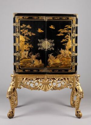  An ornate cabinet with a lacquered finish featuring gold and silver scenes on a black background, placed on a gilded rococo-style stand against a plain backdrop. Artistname and title are unknown.