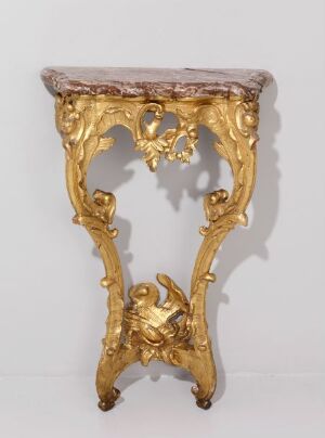  An ornate, gold-colored console table with a contoured marble top and extravagant Rococo-style scrollwork, featuring a central cartouche and dramatic legs resembling elaborate golden foliage.