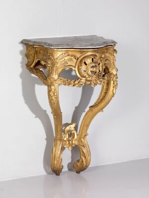  An intricately designed ornate table with a top made of dark material and gilded body featuring baroque-style decorations, set against a neutral background.