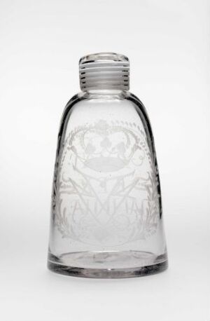  An empty clear glass bottle with an etched design on its surface, standing against a white background, with the cap missing and light reflecting off the contours of the bottle.