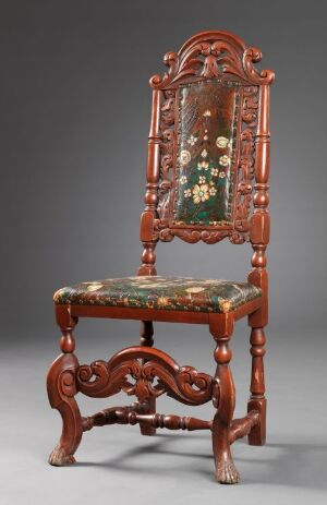  An antique wooden chair with intricate carvings and a rich reddish-brown finish. It features a tall, curved back with a central upholstered panel and seat adorned with a floral pattern. The chair stands on elegantly scrolled legs connected by a decorative crossbar, against a neutral grey background.