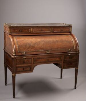  An antique wooden cylinder roll-top desk with a rich reddish-brown finish and brass hardware, featuring intricate wood inlays and standing on elegant, curved legs.