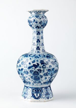  An ornate blue and white porcelain vase with a bulbous base, slender neck, and flared mouth featuring intricate floral and swirling patterns.