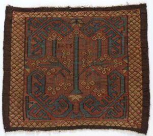 
 A square textile with intricate symmetrical patterns in terracotta red and forest green, accented by golden-yellow and white, possibly a traditional rug or fabric with an ornate tribal design.