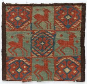  Vintage square textile with symmetrical pattern featuring central geometric motifs, stylized red animal figures, and a bordered edge in shades of red, blue, green, and brown on a beige background, showcasing traditional craftsmanship and cultural design.