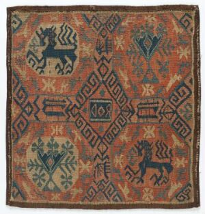  An ancient square textile with intricate patterns, featuring faded terracotta, blue, and green hues, and stylized animal motifs at each corner pointing inward towards a central diamond-shaped medallion. The textile displays a harmonious composition of geometric shapes, floral designs, and border patterns, with visible signs of age and wear.