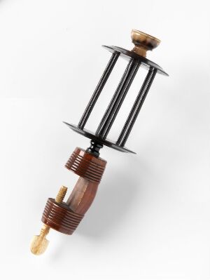  A decorative object with a light brown wooden top, three parallel glossy black rods with symmetric details, connected to a brown spiraled component which ends in a cream-colored horn-like protrusion, all against a white background. Artist and title are unknown.