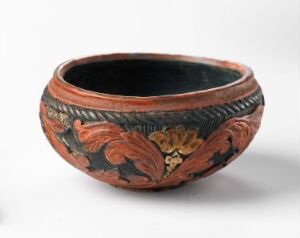  A small ceramic bowl with a black interior and a decorated exterior featuring terracotta, black, and yellow-tinged floral patterns, with a chevron design running along the rim.