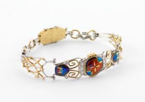  An elegant gold-tone bracelet with an openwork link design and colorful gem-like insets, featuring deep blues, vibrant reds, marbled ocean blue-green, and fiery orange-red, placed against a pure white background.