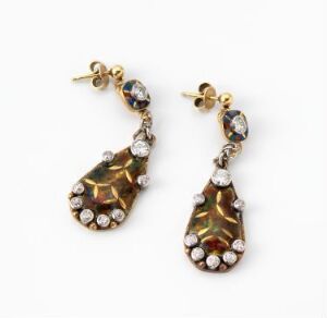  A pair of vintage-style drop earrings with teardrop-shaped golden brown gemstones, encircled by small clear crystals, and a dark blue or green round gemstone on the post, all set in gold-tone metal.