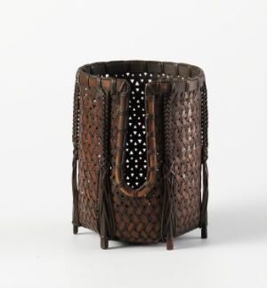 
 A dark brown cylindrical container with intricate geometric patterns and a black interior rests on small feet, suggesting refined craftsmanship.