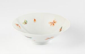  A porcelain bowl with a glossy finish and hand-painted flowers in soft orange and green hues, set against a white to gray gradient background. Artist name and title are unknown.