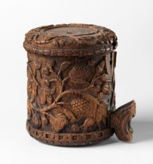  A detailed wood-carved cylindrical container with a lid, featuring relief designs of wildlife in a forest setting. It's a medium-to-dark brown color, and there's a carved handle on the side of the cylinder. Artist name and title are unknown.