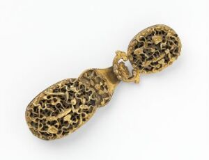  An ornate golden object with an openwork filigree design, consisting of two connected oval sections with a hinged clasp, set against a white background.