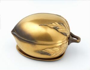  A decorative, clamshell-shaped golden purse with a polished finish and a stylized pattern engraved on one side, featuring a small gold handle. Artist name and title remain unknown.