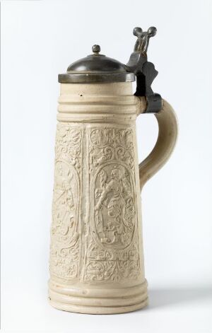  A traditional ceramic beer stein with a light beige, intricately embossed body, featuring a metallic, dome-shaped lid with a thumb lever in a gunmetal color, against a white background.