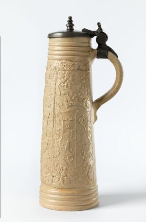  An antique beer stein made of golden-brown metal with embossed designs covering its body, featuring a curved handle and a hinged lid with a thumb lever.