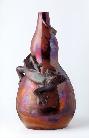  A sculpturally crafted vase with an asymmetrical neck and an abstract embellishment around its midsection, displaying rich brown to amber hues and patches of iridescent purple and blue, suggesting an artisan-crafted ceramic piece.