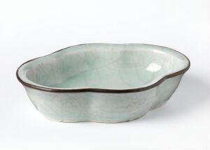  A pale green-blue ceramic bowl with a glossy finish and a brown rim, displaying an organic and irregular form on a plain white background.