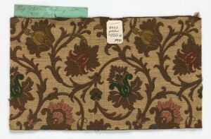  An image of a rectangular piece of fabric with a beige to light brown background, adorned with an ornate, repeating pattern of stylized dark brown, rust-red, and dark green floral motifs. A white sticker with text is apparent in the center, and a paper label is attached to the top left corner.