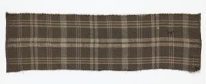  A long, rectangular piece of plaid fabric in shades of medium brown, tan, and cream, with a classic checked pattern consisting of intersecting horizontal and vertical stripes of varying thickness.