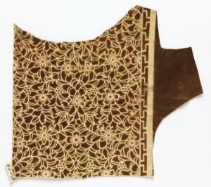  An ornate, tan and dark brown lace-like textile with floral and geometric patterns, cut into a rectangular shape with one curved edge.