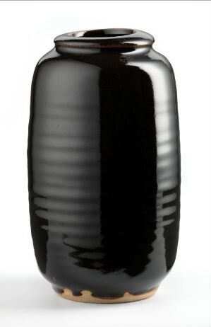  A glossy black ceramic vase with a slightly bulging middle, vertical ribbed texture, and subtle brown undertones near the base, against a neutral background.