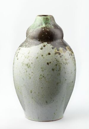  A handcrafted ceramic vase with a rounded base and a short neck, featuring a speckled cream and gray gradient on the lower half transitioning to a muted green glaze with darker top near the opening, against a plain white background. Artist name and title are unknown.