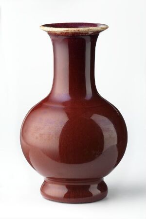  A deep red, glossy vase with a slender neck and a rounded body, accented with a light-colored band around the lip, against a white background.