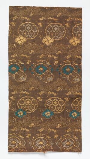  An antique, vertical textile with a deep brown background featuring a pattern of golden medallions and fewer teal circular motifs, all with intricate detailing evoking a historical and traditional aesthetic.