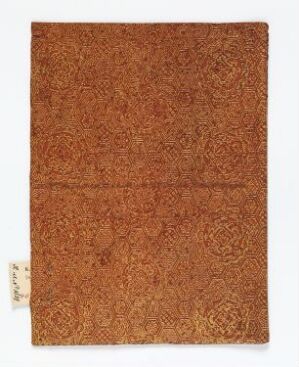  A folded, textured object in various shades of earthy brown with intricate swirling patterns, a horizontal crease, and a small identification tag in the corner. Artist name and title are unknown.