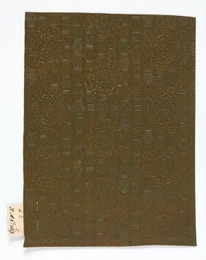  A rectangular piece of textured artwork with a complex pattern of raised dots on a deep brown background, featuring a small label with Asian characters in the lower left corner, against a light neutral backdrop. Artist name and title are unknown.