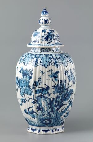  An ornate blue and white porcelain vase with a lid, displaying intricate floral and foliate designs, set against a light grey background.