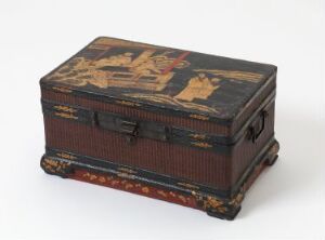  An antique, rectangular, dark-colored box with traditional East Asian decorations including a central pictorial scene on the lid, metal clasps on the front, and ornate golden and red patterns along the edges, displayed against a light background.