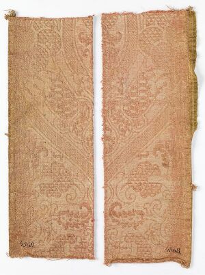  Two vertical textile panels in pale peach with intricate raised floral embroidery, placed side by side against a neutral background, displaying signs of age with frayed edges and a delicate, elaborate design.