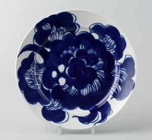  A circular ceramic plate with intricate blue floral patterns on a white background, featuring a large symmetrical flower in the center and various other flower motifs surrounding it.