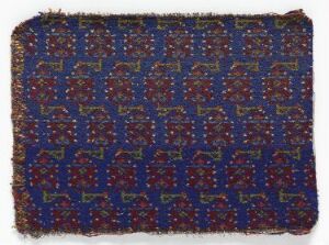  An antique textile with a deep blue background featuring a golden and red pattern of stylized animals and intricate floral and geometric motifs, with edges that are frayed, suggesting historical significance.