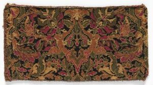  An antique textile featuring an elaborate, symmetrical pattern with a dark background and richly colored motifs in red, green, and gold, hinting at a historical or traditional origin.