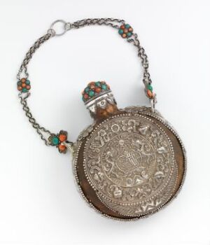  An intricate silver flask with a chain necklace, showcasing embossed designs and adorned with colorful red and turquoise accents, displayed against a light background.